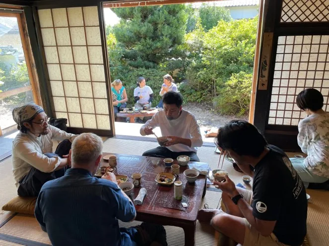 Travellers sitting down to a meal in a traditional room opening onto a garden