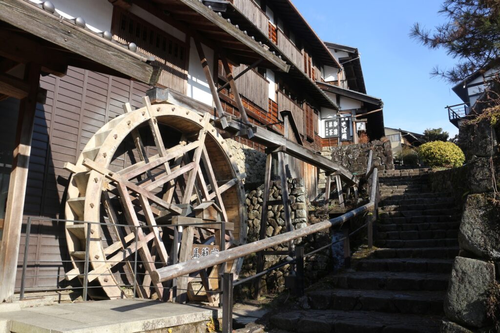 A large wooden waterwheel beside the stone-stepped street of Magome-juku
