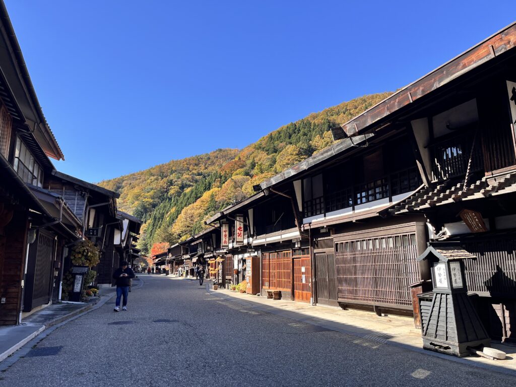 Wooden merchant houses lining the main street of Narai-juku, with autumn mountains behind