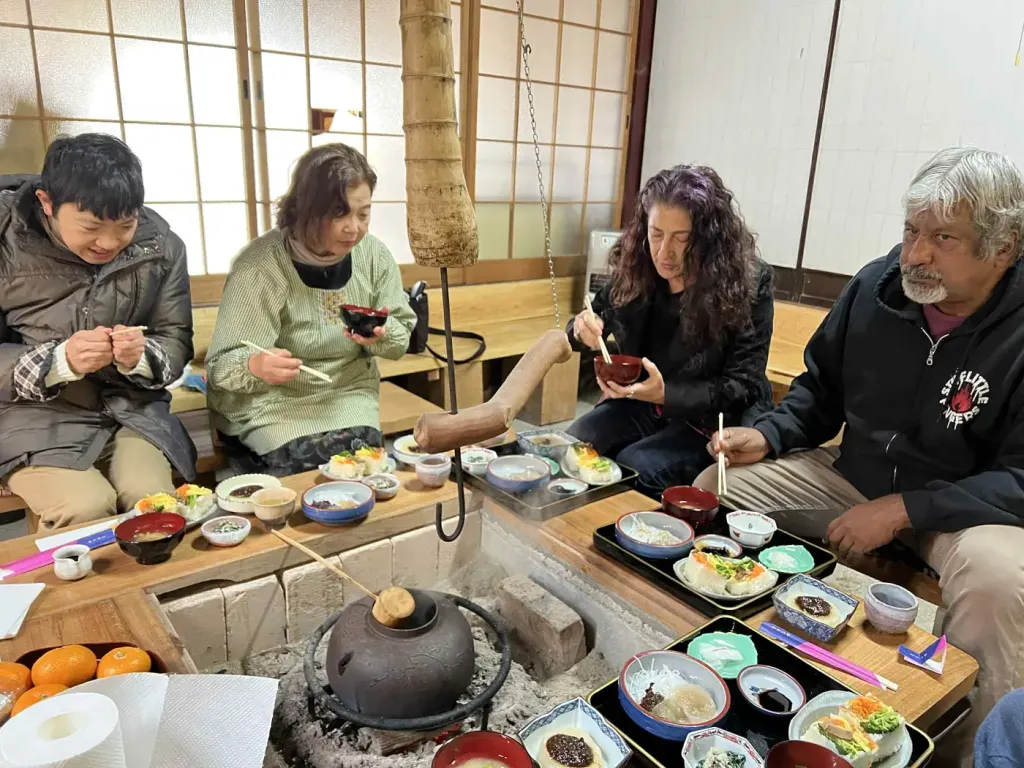 Travellers sharing a home-cooked meal around a low table at a farmhouse near Hagi