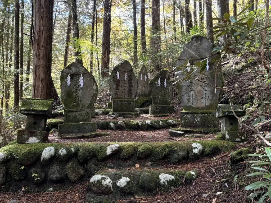 A row of weathered stone Buddha statues standing beside the Nakasendo trail