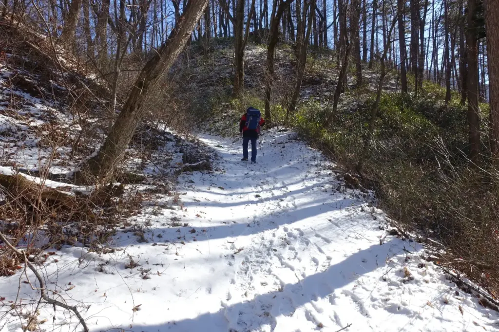 A lone hiker climbing a snow-covered section of the Nakasendo in winter