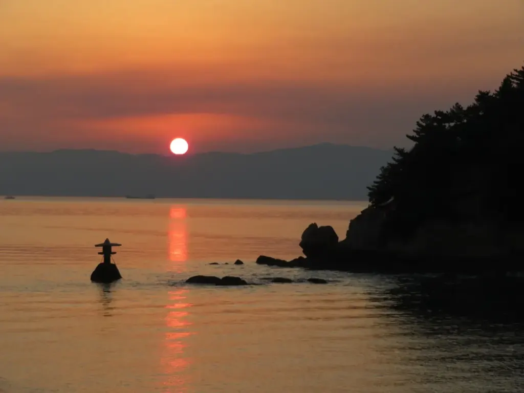 The sun setting over the Seto Inland Sea with a small rock in the foreground
